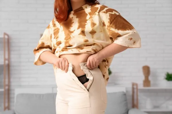 Image of woman trying to do her trousers up after pregnancy weight gain Gateshead